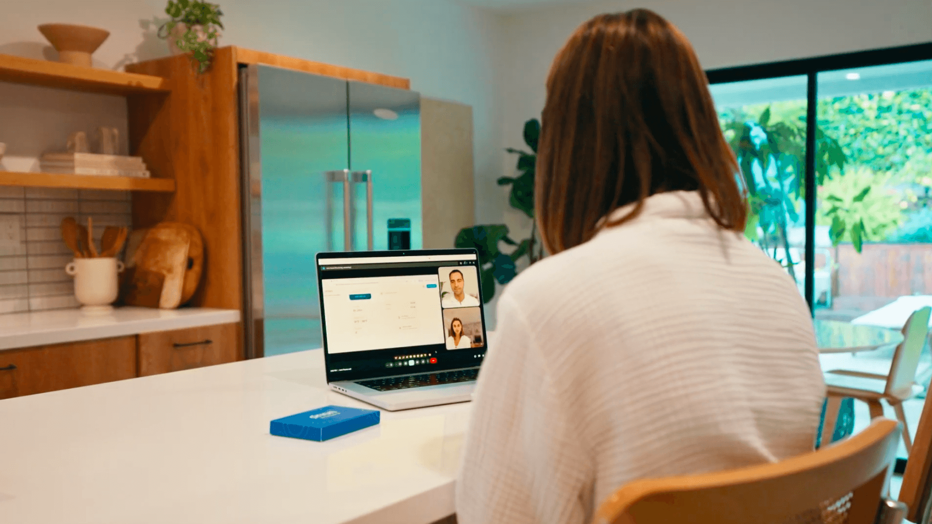 Woman on a 1:1 video call with an Orion sleep advisor, reviewing her sleep test results on a laptop at a home desk