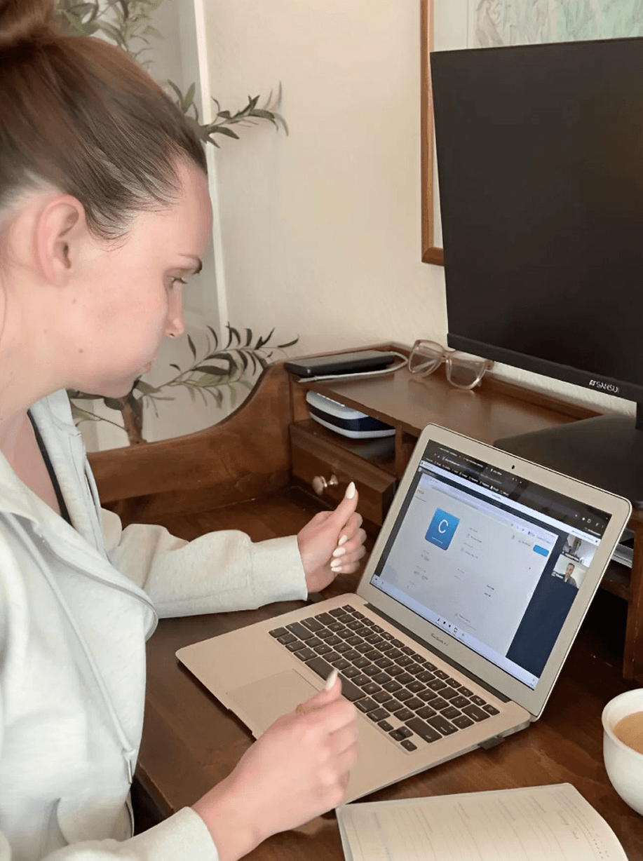 Woman on a 1:1 video call with an Orion sleep advisor, reviewing her sleep test results on a laptop at a home desk
